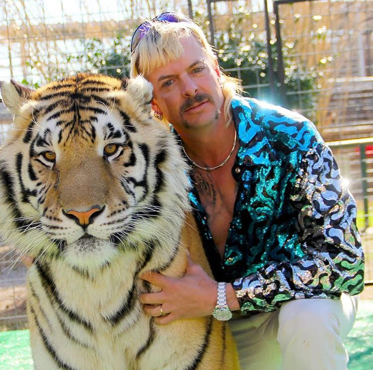 Unpredictable Joe Exotic poses with a large tiger.