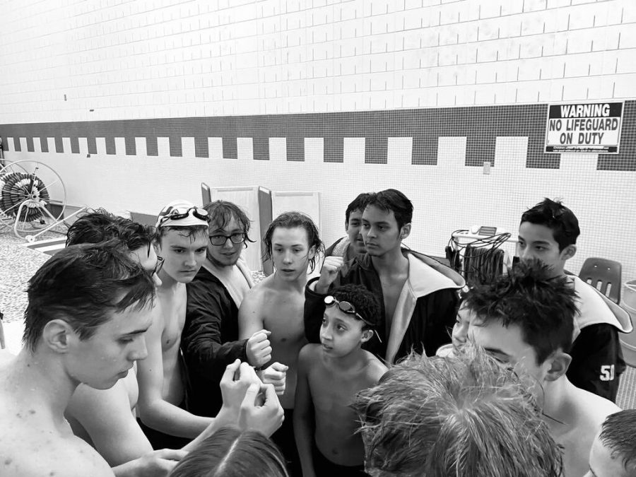 The boys swim team huddle up for a break.