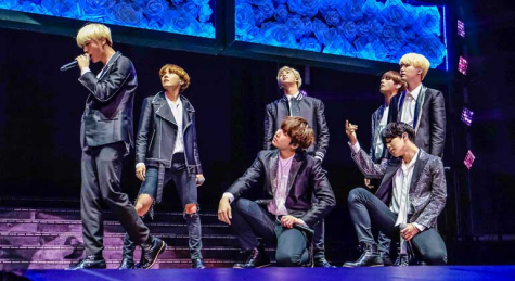 The members of ONEUS pose on stage while performing.