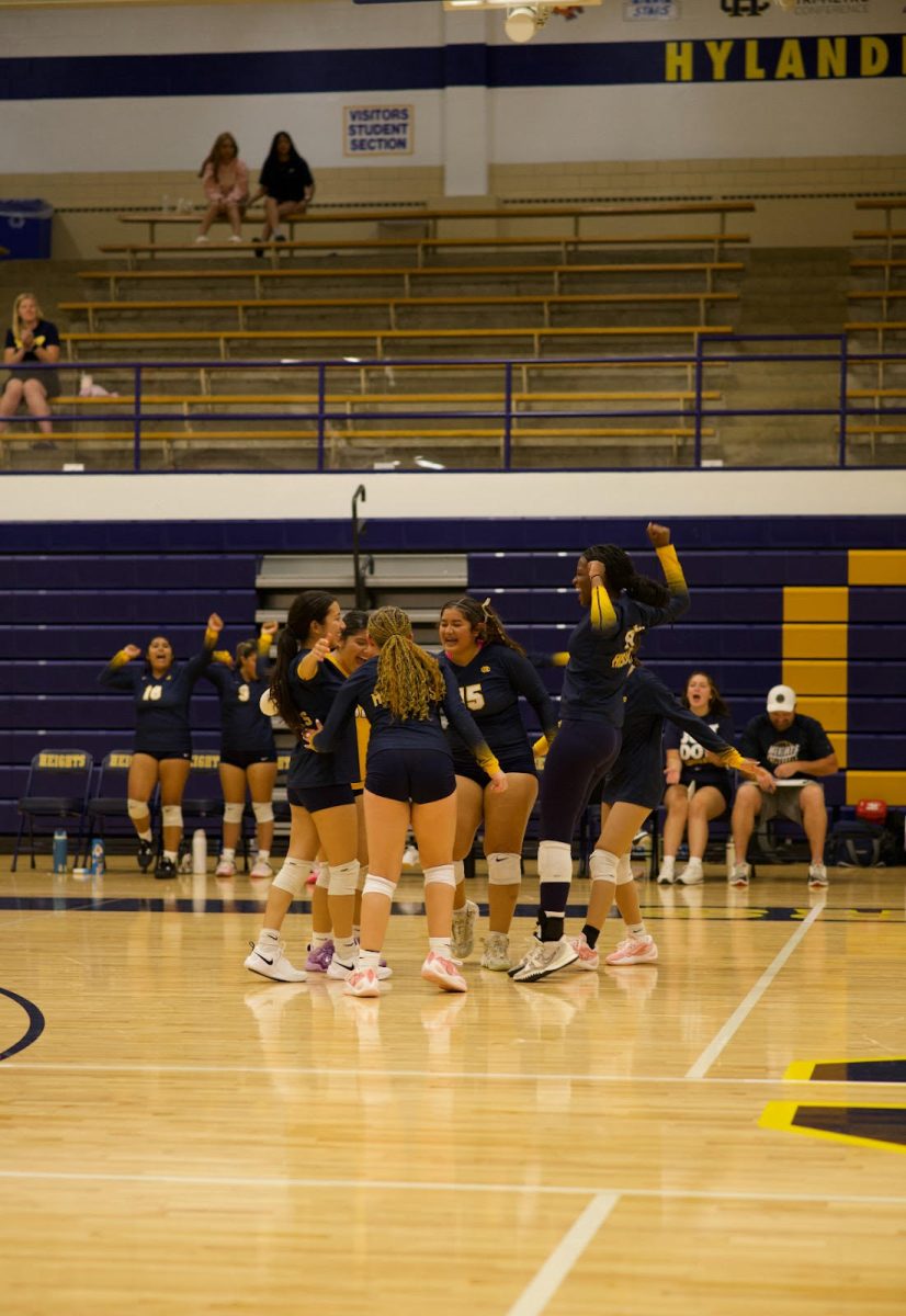 An enthusiastic girls' varsity volleyball team celebrates a win.