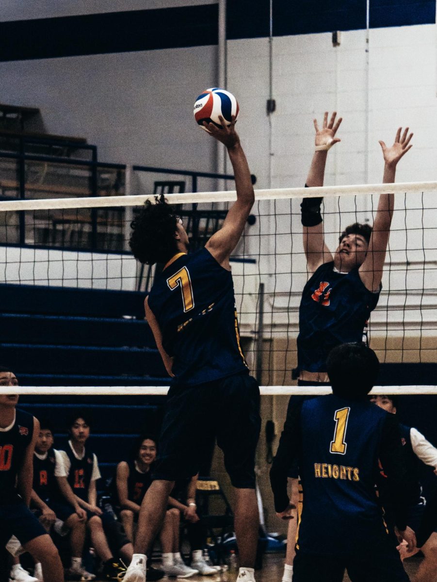 Justin Hauglid (12) prepares to spike the ball against Totino-Grace with Bryan Velez (12) poised to help defend.